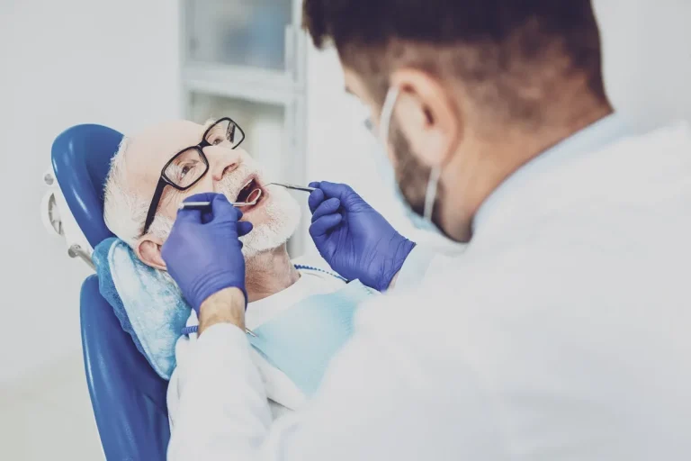 Mature man opening mouth while demonstrating his teeth to doctor